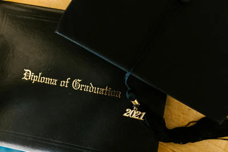 Close-up of graduation diploma with a mortarboard and 2021 tassel, representing academic achievement.