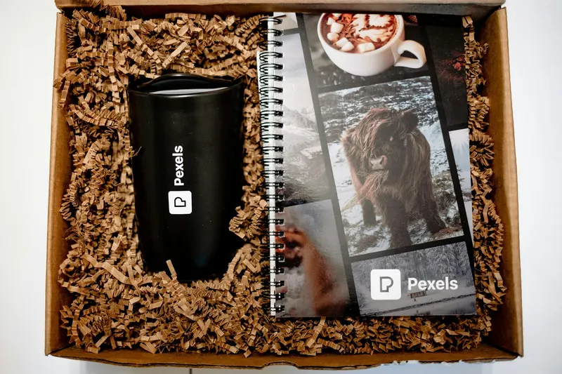 Close-up of a branded gift set featuring a tumbler and a notebook with shredded paper packaging.