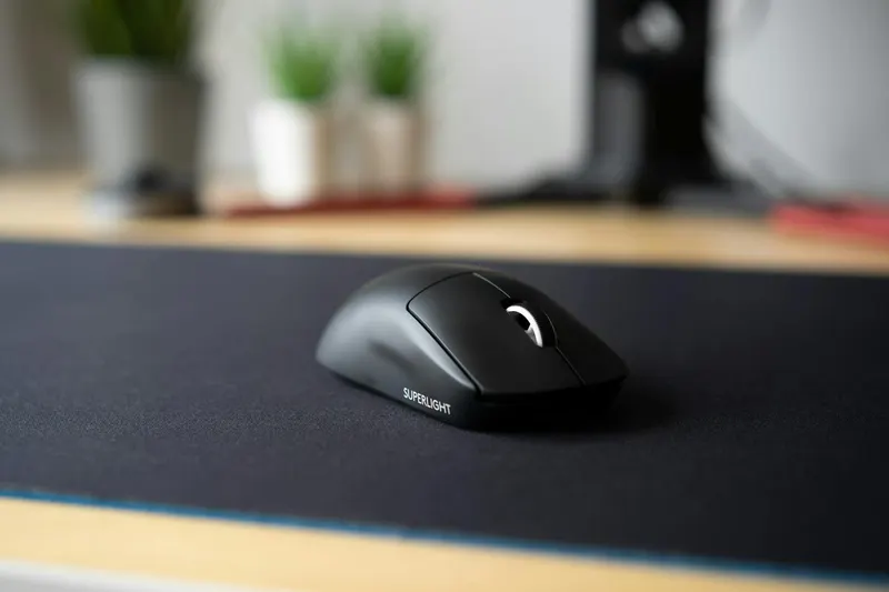 Sleek black wireless mouse on a modern desk with a blurred background, emphasizing minimalism.