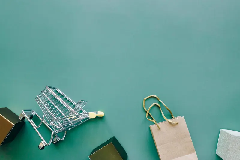 Top view of a shopping cart and bag on a blue background, ideal for retail themes.