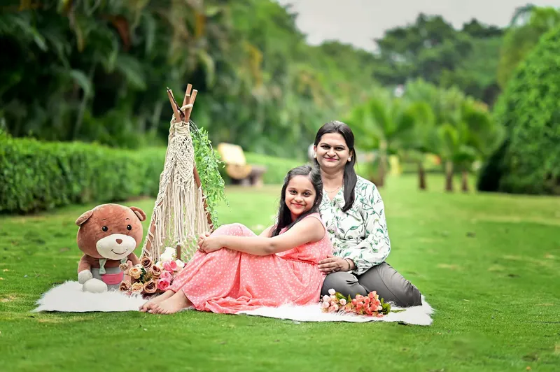 A joyful mother and daughter enjoy a picnic setting in a vibrant green garden.